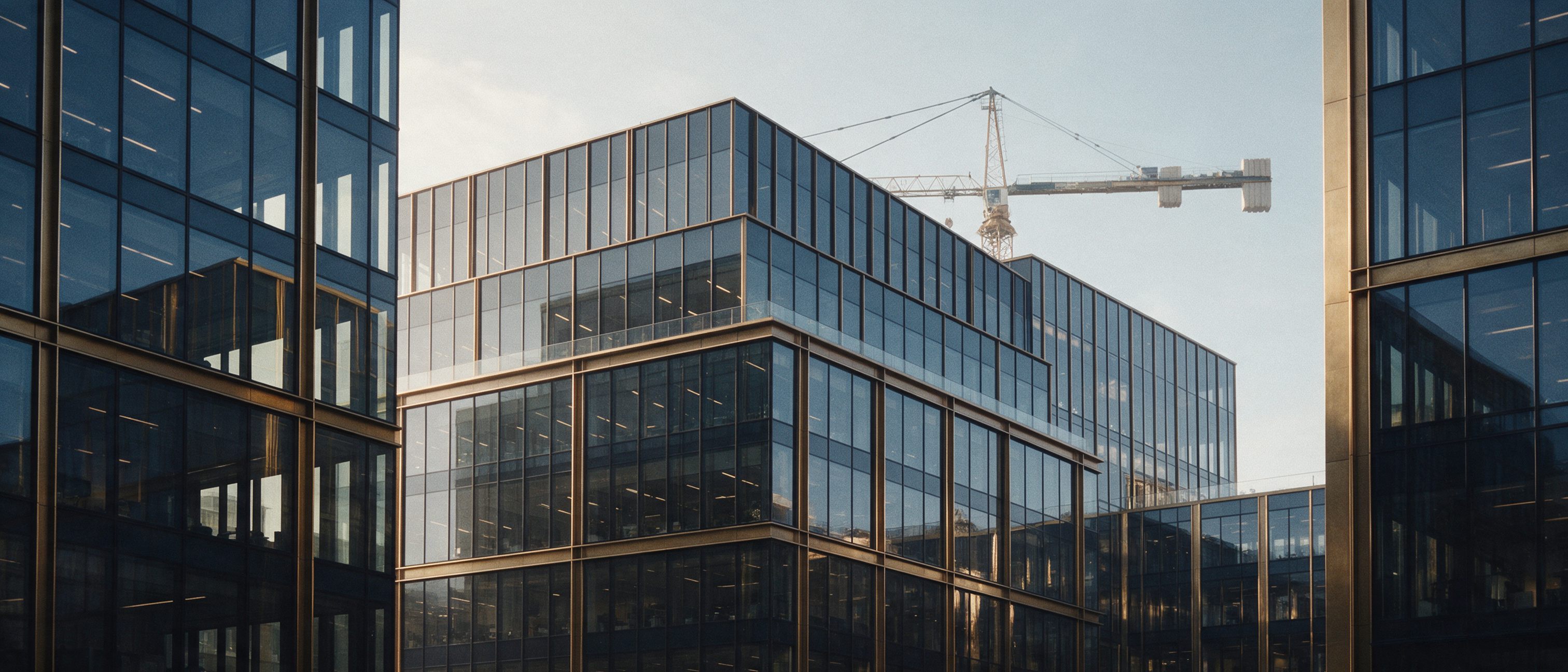 Moderne Bürofassaden mit Baukran im Morgenlicht